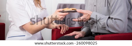 Close-up of care assistant giving pensioner cookies