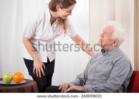 Image of young nurse caring about elder man