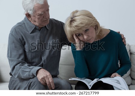 Senior man hugging upset wife having financial problems