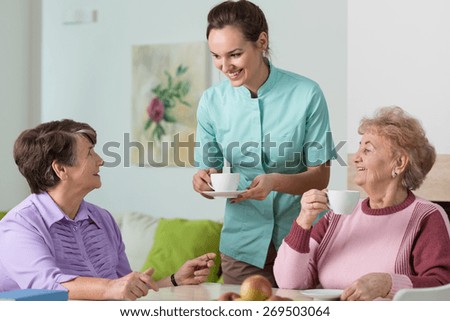 Two old women and a nurse having a cup of tea