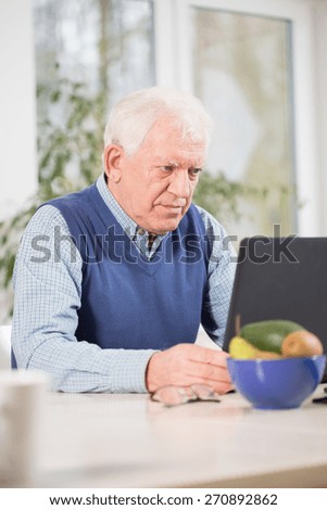 Focused elderly man using laptop to his work