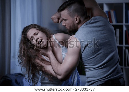 Aggressive strong man hitting screaming woman with fist