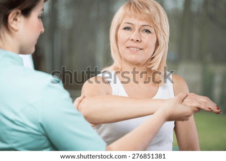 Young female physical therapist diagnosing painful arm