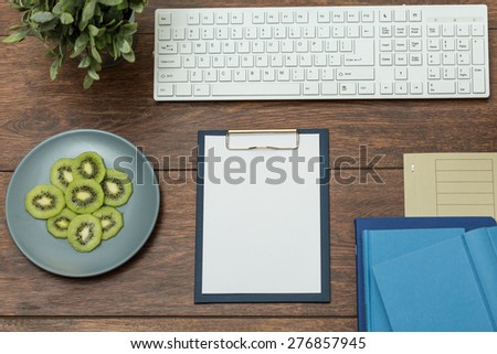 Tidy wooden office desk with plate of fresh kiwi