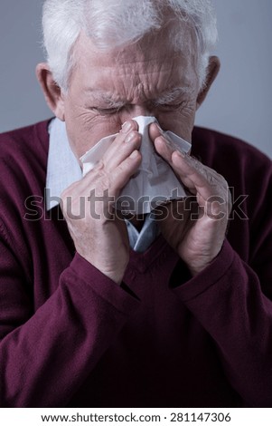 Old man with infection blowing his nose