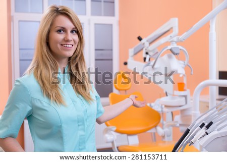 Young attractive stomatologist presenting her dental unit