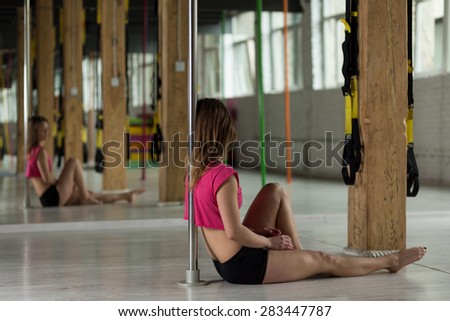 Pole dancer sitting on the floor and resting after training