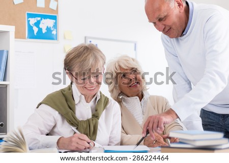 Teacher helping elder student in the collage