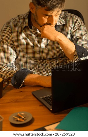 Single man is tired but he works on his computer