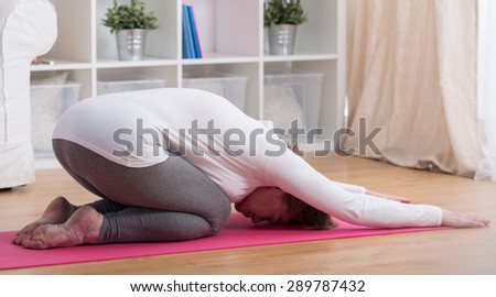 Aged lady stretching the spine in yoga child pose
