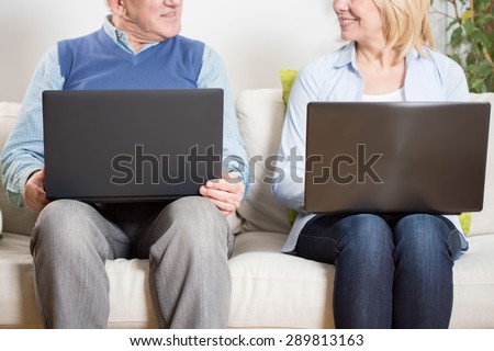 Elder couple sitting on the sofa with their notebooks