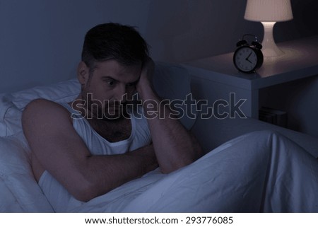 Exhausted thoughtful man in bed in early morning