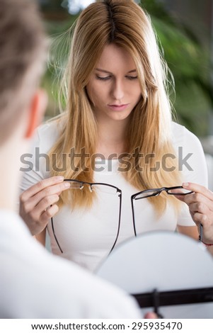 Beauty girl choosing glasses in optical store