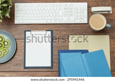 Clipboard and books on wooden office desk