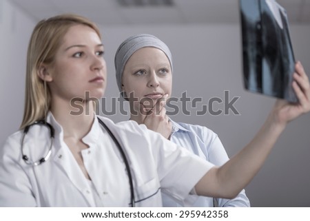 Pretty doctor looking for metastasis on cancer woman\'s xray