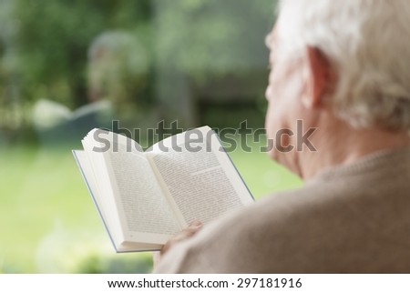 Elder man sitting and reading interesting book blur