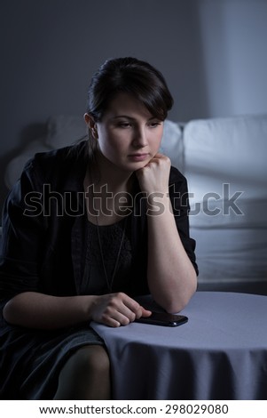 Pretty young woman sitting in loneliness at home