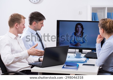 Three workers having business conference online with colleague