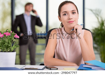 Secretary sitting at the desk and her boss in background