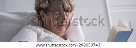 Older sick lady resting with book at hospital