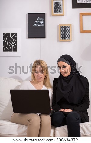 Christian and muslim girls watching film on laptop