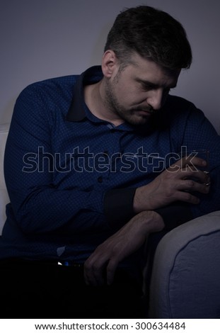 Young male alcoholic drinking alone at home