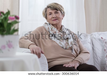 Melancholic elderly pensioner sitting on the sofa