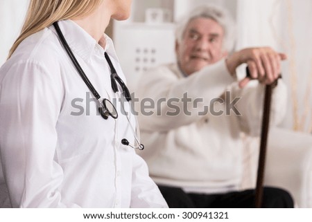 Young female doctor diagnosing disabled senior man