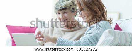 Two women are watching something on laptop screen