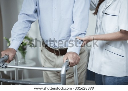 Disabled man using walking frame during rehabilitation