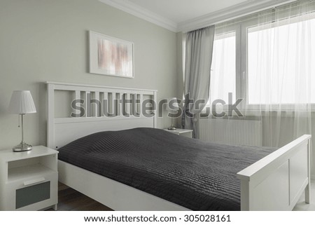 Photo of king size white wooden bed with black bedding