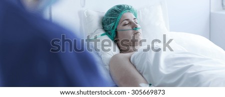 Female patient after surgery lying with nasal cannula in hospital bed