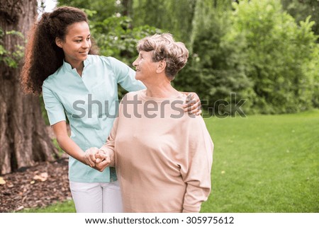 Elder woman and caregiver walking in the park