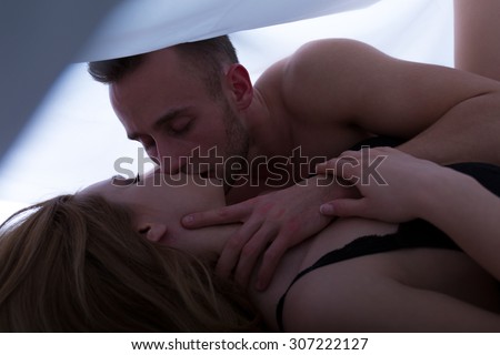 Sexy couple caressing and kissing in bed