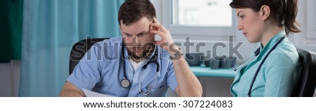Two young doctors are examining patient\'s results, panoramic view