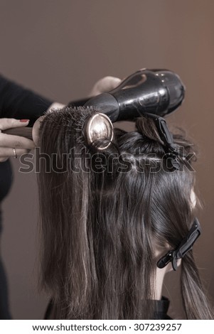 Close-up of female hair stylist using hairdryer