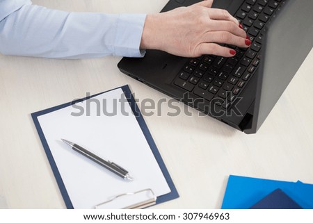 View from the top of elderly woman writing down on computer