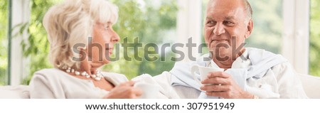 Elder man and woman are drinking coffee
