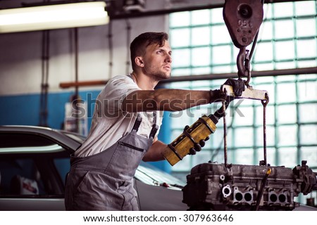 Image of auto workshop worker using engine hoist