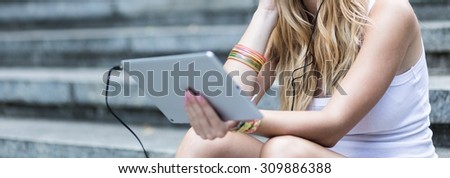 Girl sitting on the steps is holding portable device