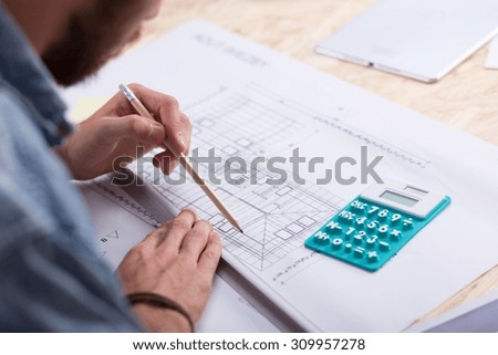 Architect with blueprint and calculator estimating project cost
