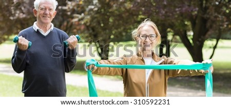 Panorama of senior sporty pair exercising on fitness trail