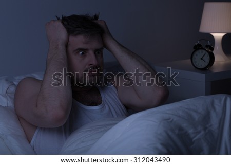 Horizontal view of mentally ill man at night in bed