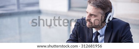 Businessman with headphones listening music at work