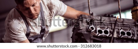 Young garage mechanic repairing auto engine - panorama
