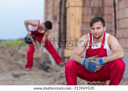 Young tired construction worker sitting on breeze-block