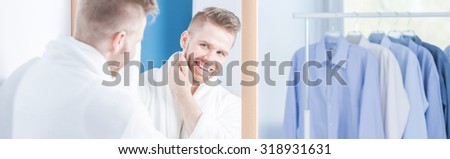 Panoramic view of smiling narcissistic male checking his complexion