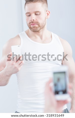 Image of handsome muscular man taking photo of himself