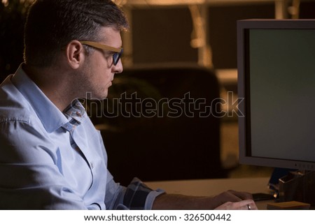 Busy man in glasses using computer at work