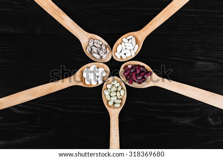 A colorful of beans in wood spoon on wood background